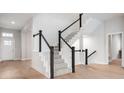 A stylish staircase featuring wood floors, white risers, black handrail, and neutral carpet on the treads at 11338 Briargate Dr, Fishers, IN 46055