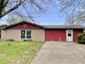 A cozy single-story house with a well-kept lawn, a concrete driveway, and a combination of stone and siding at 1221 S Catherwood Ave, Indianapolis, IN 46203