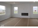 Unfinished living room with an electric fireplace, three windows, and cardboard covering the floor at 17039 Silo Ridge Way, Noblesville, IN 46060