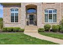 Charming entrance with a stone archway, black door, and manicured greenery along a stone walkway at 3384 Homestretch Dr, Carmel, IN 46032