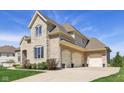 Spacious three-car garage with a paved driveway, enhanced by a blend of stone and brick exterior at 3384 Homestretch Dr, Carmel, IN 46032