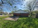 Rear view of brick home with grassy area, driveway and adjacent shed at 3755 N Brentwood Ave, Indianapolis, IN 46235