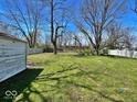 View of spacious backyard with grass and trees and a white fence at 4520 Clinton St, Indianapolis, IN 46226