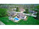 Aerial view of home showcasing the backyard pool, patio, deck, and well-manicured lawn in a verdant neighborhood at 4977 Beechwood Rd, Avon, IN 46123