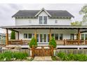 Inviting two-story home with a covered front porch, wood railing, fenced yard, and beautifully landscaped front yard at 5682 Upper Garden Way, Zionsville, IN 46077