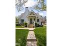 Quaint white brick home with landscaped yard and charming covered front porch with steps at 5946 N New Jersey St, Indianapolis, IN 46220