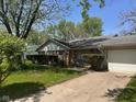 Ranch style home with a well-manicured lawn, attached garage, and mature trees under a sunny sky at 6040 Ipswich Ct, Indianapolis, IN 46254