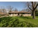 Charming single-story home with a stone facade, mature trees, and a well-maintained lawn at 614 Debra Ln, Indianapolis, IN 46217