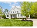 Beautiful white modern farmhouse featuring a lush green lawn and mature trees at 7602 N Pennsylvania St, Indianapolis, IN 46240