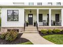 Charming front porch with black door, potted plants, and rocking chairs at 7602 N Pennsylvania St, Indianapolis, IN 46240