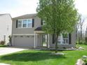 Two-story home featuring neutral siding, dark shutters, an attached garage, and a green front yard at 9045 Stones Bluff Pl, Indianapolis, IN 46113