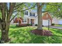Well-maintained front exterior of a two-story home with lush green lawn, mature trees, and attached two-car garage at 9099 Merrill Ct, Fishers, IN 46038