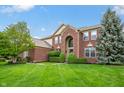 Beautiful brick home featuring a lush green lawn and mature landscaping adding to its appeal at 14145 Charity Chase Cir, Carmel, IN 46074