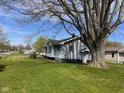 Side view of a cozy home showcasing a well-kept yard and mature trees at 1802 Poplar St, Anderson, IN 46012