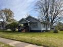 Quaint single-story home featuring a covered porch and mature trees in a serene setting at 1802 Poplar St, Anderson, IN 46012