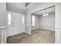 Welcoming foyer featuring hardwood floors, a chandelier, wainscoting, and natural light from the front door at 3147 Winings Ln, Carmel, IN 46074
