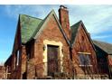 Quaint red brick home featuring a chimney, green roof, and decorative iron entry door at 3208 Brookside Pkwy N Dr, Indianapolis, IN 46218