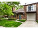 Brick townhome with attached garage, balcony, mature landscaping, and a well-manicured lawn at 354 E Arch St, Indianapolis, IN 46202