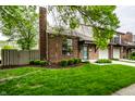Brick townhome featuring an attached garage and manicured lawn at 354 E Arch St, Indianapolis, IN 46202