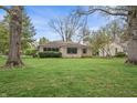 Beautiful exterior home showcasing a well-manicured lawn and mature trees at 3818 Kessler Boulevard East Dr, Indianapolis, IN 46220