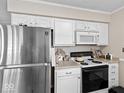Functional kitchen featuring white cabinetry, stainless steel refrigerator, and a range stove, ready for your culinary creations at 390 Lakeview Dr, Noblesville, IN 46060
