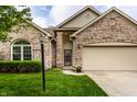 Close-up of a brick-front home highlighting the covered entry, manicured lawn, and attached two-car garage at 5845 Arrowleaf Ln, Carmel, IN 46033