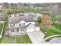 Aerial view of a two-story house with a three-car garage situated on a lot with a lake in the background at 6507 Tram Ct, Indianapolis, IN 46260