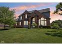 Beautiful two-story brick home with a manicured lawn at sunset at 7323 Elm Ridge Dr, Indianapolis, IN 46236