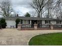 Charming ranch home with a brick facade, showcasing a well-manicured lawn and driveway with a two car garage at 7334 E 14Th St, Indianapolis, IN 46219