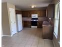 Well-lit kitchen featuring tile flooring, wooden cabinetry, and modern appliances at 7450 Cobblestone W Dr, Indianapolis, IN 46236