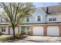 Townhouse with a brick facade, white garage door, and a well-manicured front yard with a young tree at 9575 Thradd St, Fishers, IN 46038