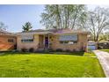 A classic brick home with awnings, complemented by a lush green lawn at 1031 N Lesley Ave, Indianapolis, IN 46219