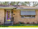 Close-up of a brick facade, awnings, with a bold purple front door at 1031 N Lesley Ave, Indianapolis, IN 46219
