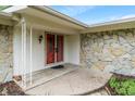 Covered front porch with stone veneer, white posts, and a red front door enhances curb appeal at 11415 Central E Dr, Carmel, IN 46032