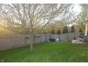 Spacious backyard surrounded by a wooden fence with green lawn, a mature tree and patio seating at 12214 Cold Stream Rd, Noblesville, IN 46060