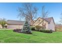 Well-maintained home with landscaping features, including trees and shrubs, enhancing curb appeal at 168 Yorkshire W Blvd, Cumberland, IN 46229
