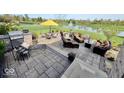 Expansive backyard stone patio complete with outdoor seating, a grill, and views of a scenic pond with fountain at 18756 Brookston Ln, Noblesville, IN 46062