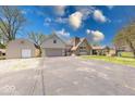 Wide view of the home's exterior with a large driveway, detached garage, and well-maintained lawn at 260 17Th St, Columbus, IN 47201