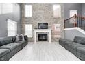 Bright living room featuring a cozy fireplace, dark gray sofas, wood floors and tall windows at 5954 Crowley Pkwy, Whitestown, IN 46075
