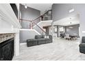 Open-concept living room with a fireplace, staircase with dark wood railing, and a view into the dining area at 5954 Crowley Pkwy, Whitestown, IN 46075