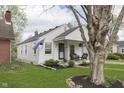 Charming one-story home with cozy porch and manicured lawn, framed by mature trees at 6180 Crittenden Ave, Indianapolis, IN 46220