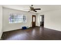 Bright living room featuring hardwood floors, white walls, a ceiling fan, and a large window at 7212 E Pleasant Run Pkwy S Dr, Indianapolis, IN 46219