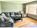 Comfortable living room featuring hardwood floors, a large window, and a comfortable sectional at 8230 E 11Th St, Indianapolis, IN 46219