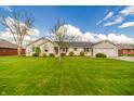 Beautiful one-story house featuring lush green lawn, mature trees, and well-maintained landscaping at 838 Deerfield Rd, Anderson, IN 46012