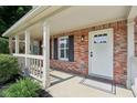 Welcoming front porch with brick accents, white columns, and a bright entrance door with glass details at 13562 Silver Spur, Carmel, IN 46032