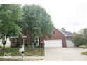 Elegant two-story brick home with a three-car garage and a spacious driveway surrounded by mature trees and landscaping at 13717 Van Buren Pl, Fishers, IN 46038