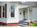 Close up of home with light siding, red brick foundation, and covered front porch at 1509 Sycamore St, Columbus, IN 47201