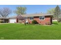 Well-maintained brick home featuring a lush green lawn and landscaped garden at 166 N Post Rd, Indianapolis, IN 46219