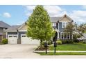 Beautiful two-story home featuring a three-car garage, well-manicured lawn, and mature tree at 2785 W High Grove Cir, Zionsville, IN 46077