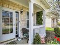 Inviting covered front porch with white railing, stone accents, and a stylish door with glass panels at 3466 Firethorn Dr, Whitestown, IN 46075